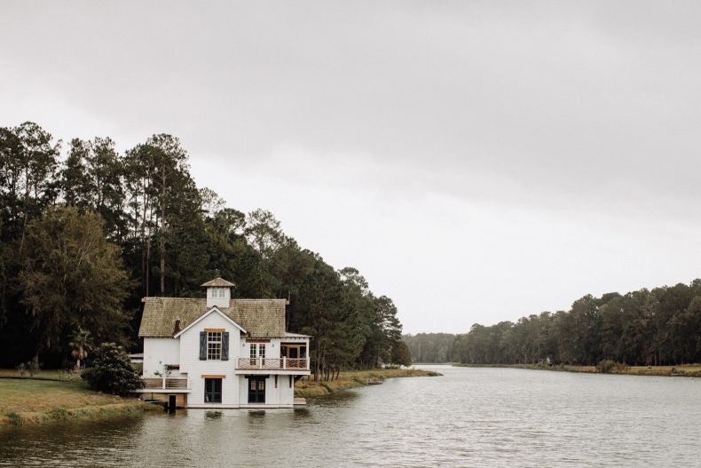 little white house with dark blue shutters built on edge of river in savannah