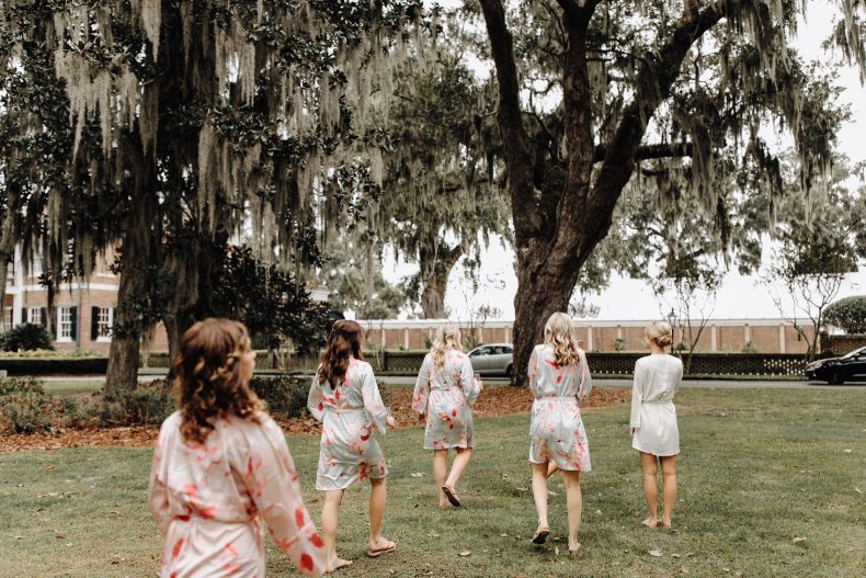 four bridesmaids in floral robes walking with bride in solid white robe on ford plantation property